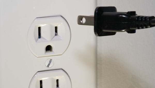 Black male plug in front of electric socket